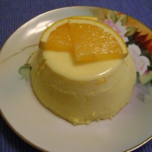 A creamy dessert topped with orange slices on a floral plate.