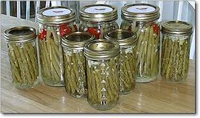 Glass jars filled with pickled green beans and cherry tomatoes.