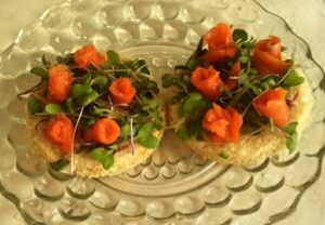 Two crackers topped with avocado and small carved carrot roses.