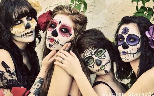 Three women with colorful sugar skull makeup for Day of the Dead celebration.