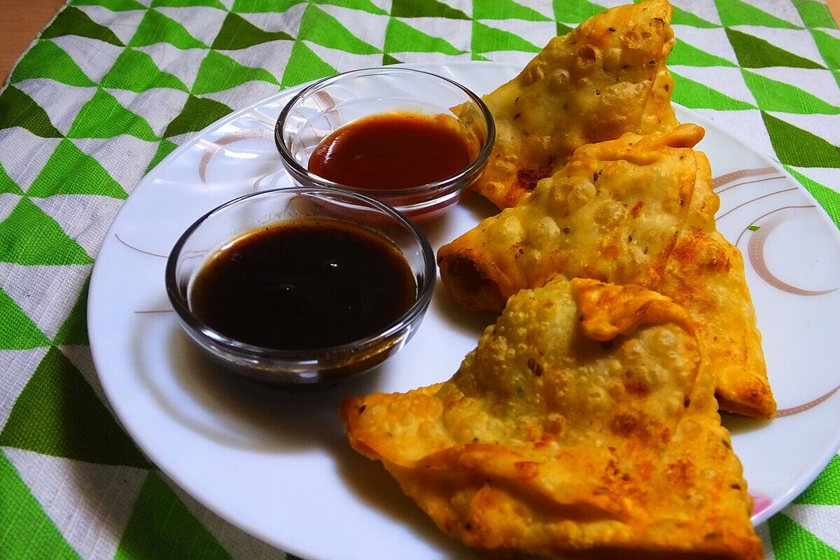 Plate of fried samosas with two dipping sauces.
