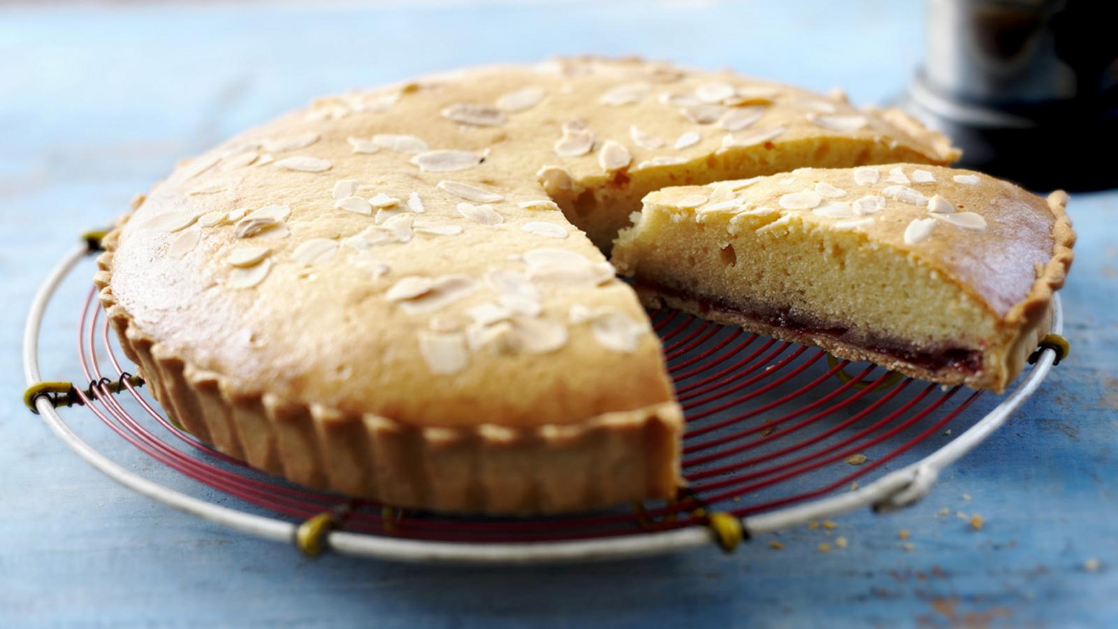 A round cake with a slice removed, resting on a wire rack.
