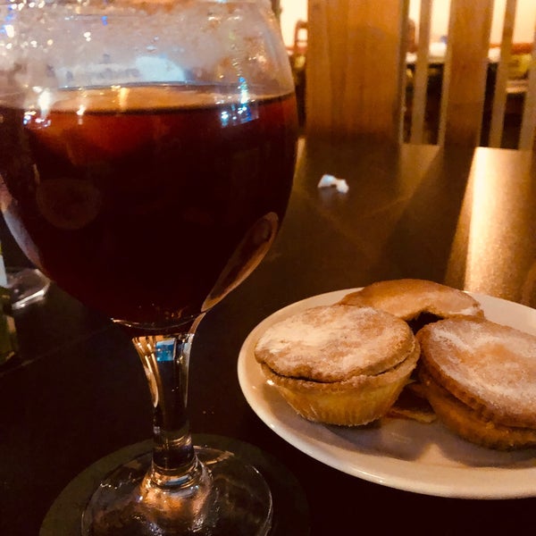 A glass of red wine next to two powdered sugar-covered pastries on a plate.