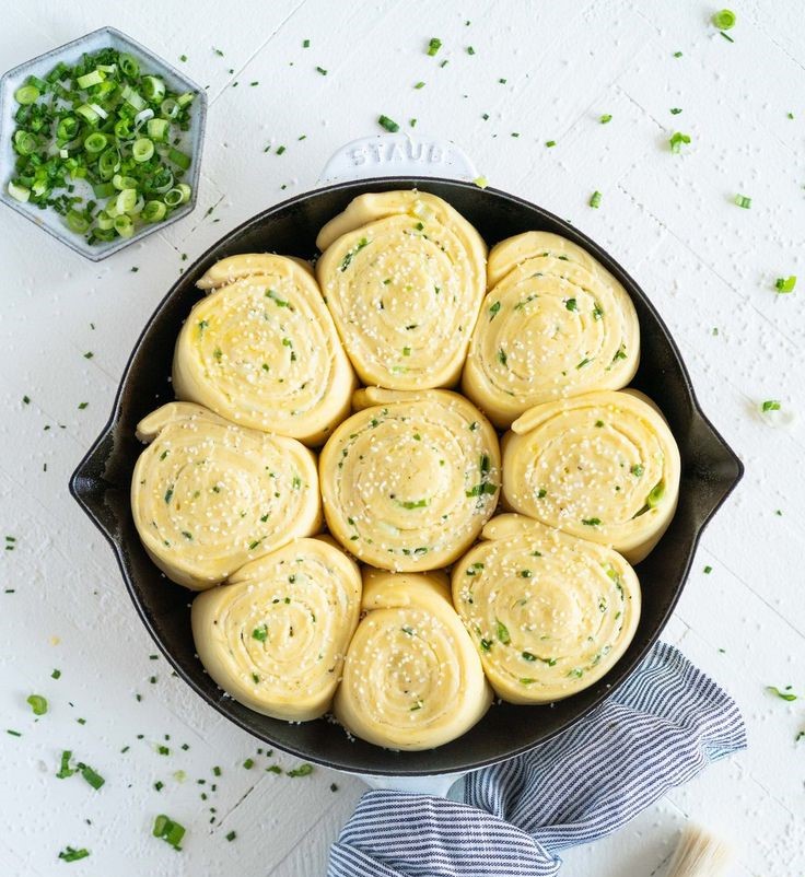Skillet filled with seasoned garlic butter rolls topped with herbs.
