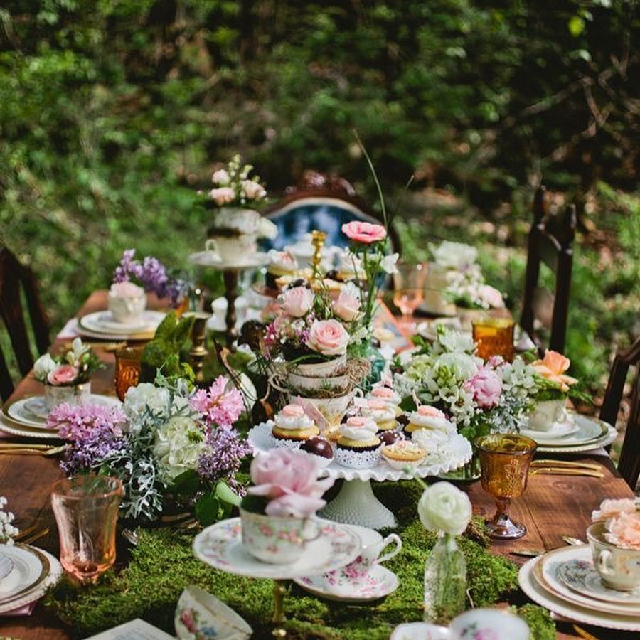 Elegant outdoor tea party setup with flowers and pastries.