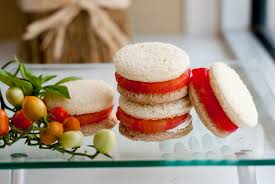 Colorful layered macarons with white, red, and orange hues on a reflective surface.
