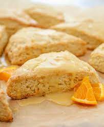 Freshly baked orange scones glazed with icing and garnished with orange slices.