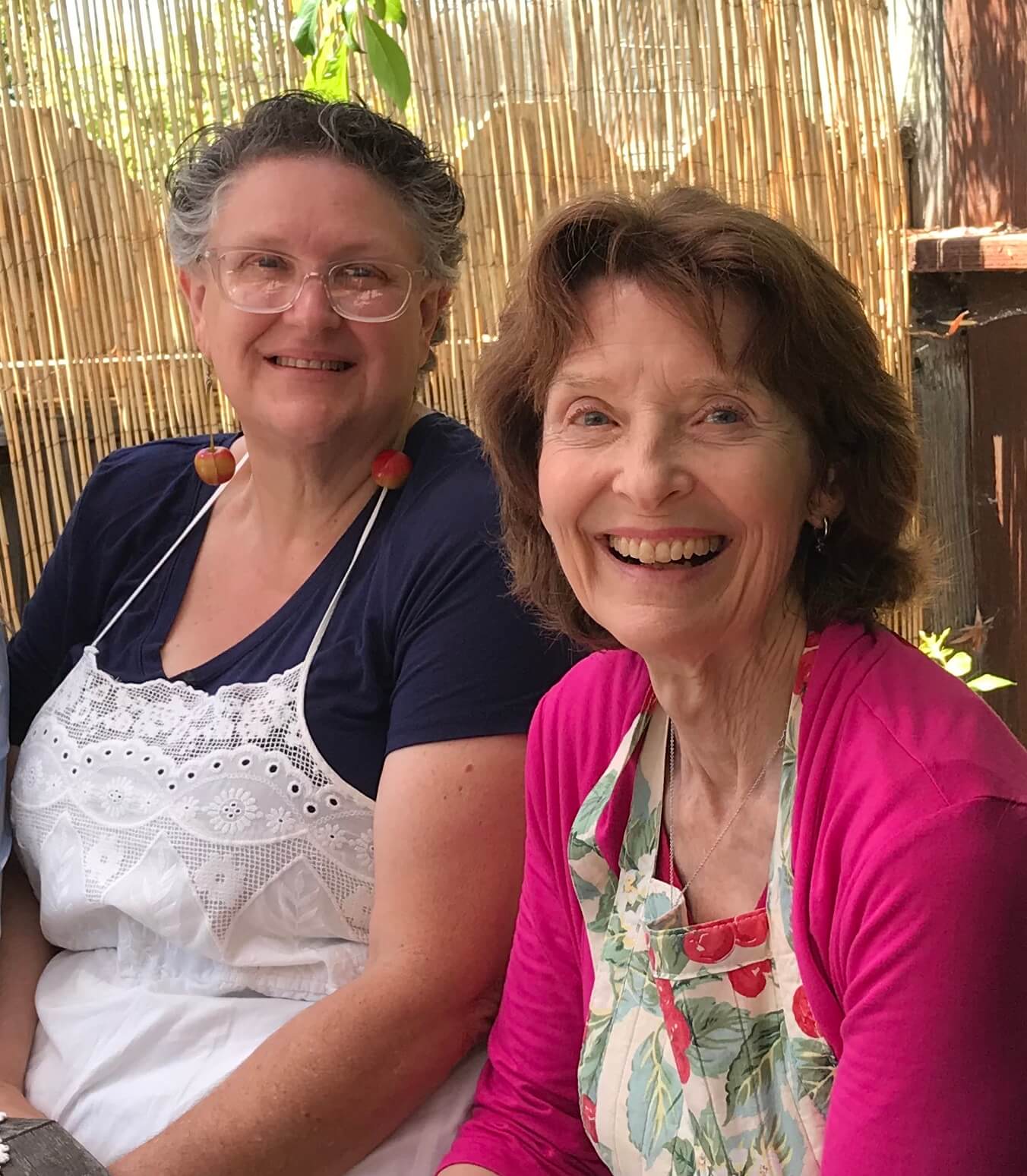 Two smiling women sitting closely together, enjoying the moment.