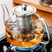 A glass teapot brewing tea on a stovetop burner.