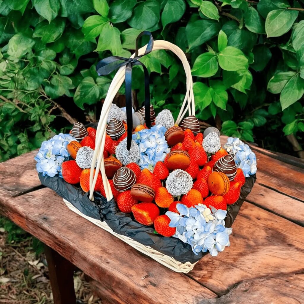 A basket filled with red and blue berries on a wooden surface.