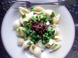 Pasta shells with green peas and bacon bits.