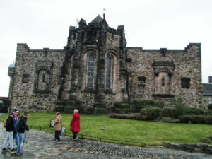 Historic stone castle with tourists walking nearby.