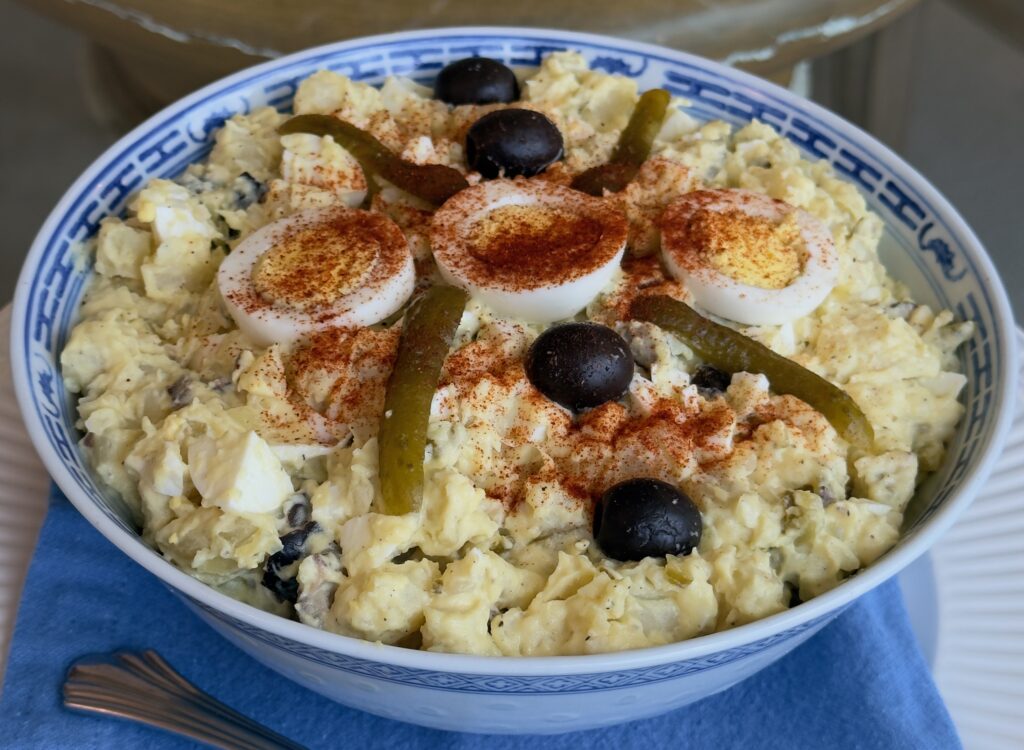 A bowl of hummus garnished with olives and spices.