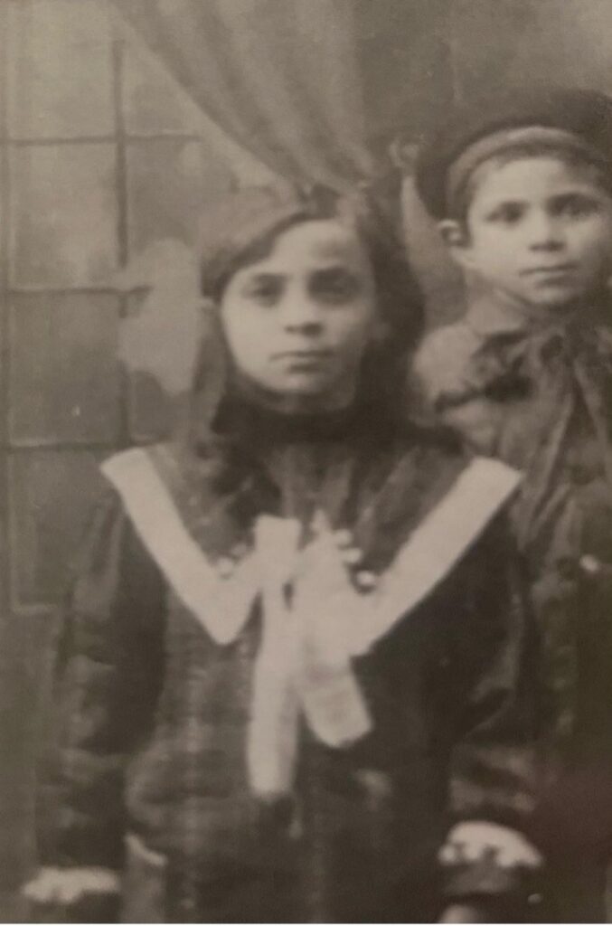 Black and white photo of a young girl in vintage clothing.