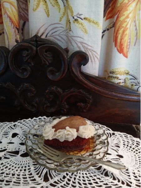 A dessert topped with whipped cream on a lace-covered wooden table.