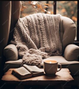 Cozy chair with blanket, book, and candle.