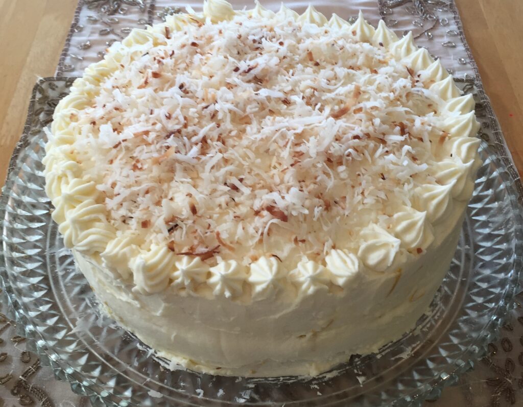 A beautifully decorated white frosted cake with nuts on top.