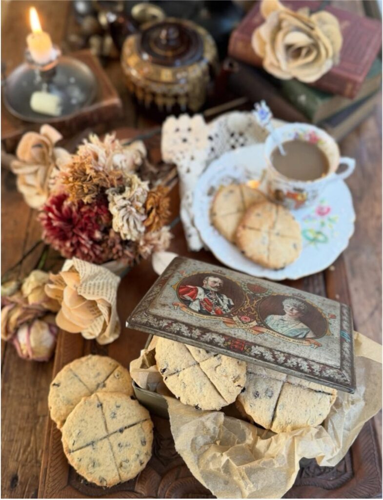 A cozy tea setup with cookies, dried flowers, and a decorative box on a wooden surface.
