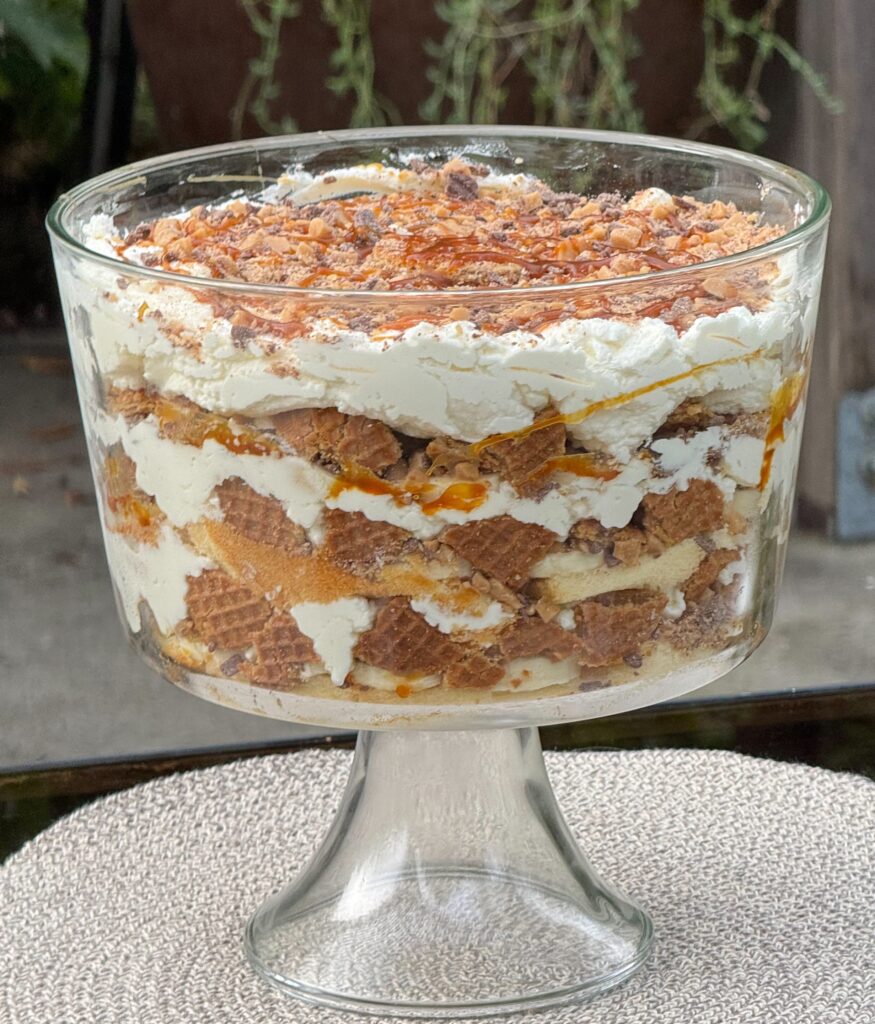 Layered dessert with cream and crumbled cake in a glass bowl.