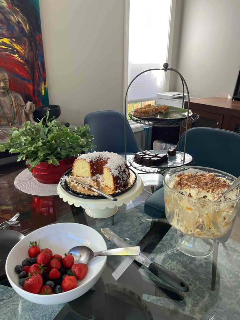 A dessert display with cake, berries, and a tiered tray on a dining table.
