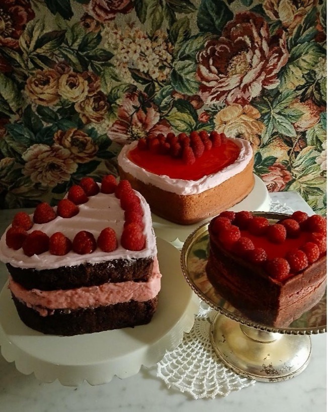 Heart-shaped cakes with raspberries on stands.