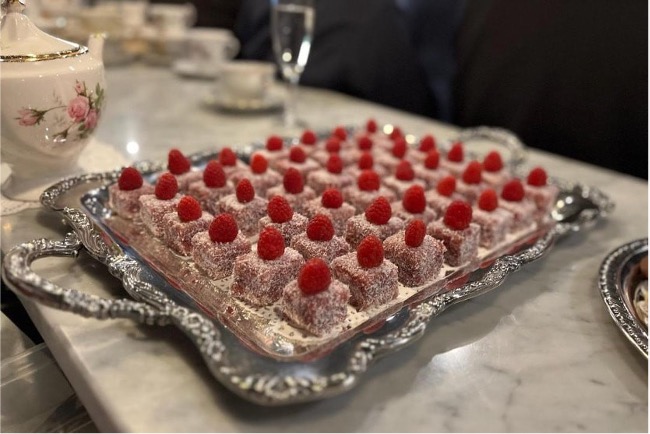 Raspberry-topped desserts on ornate silver tray.
